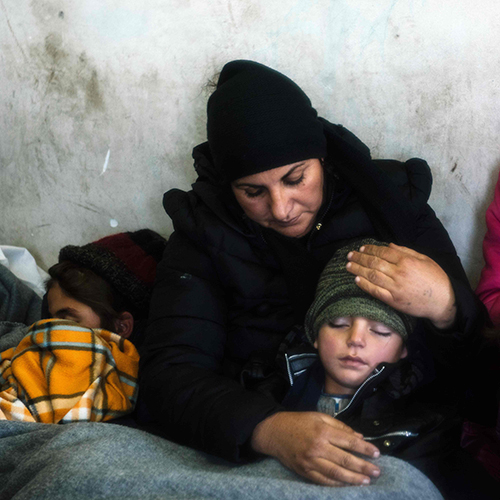 A woman comforts her sleeping child while waiting with other migrants and refugees at a train station for a train in the southern Serbian town of Presevo on Wednesday (AFP photo)